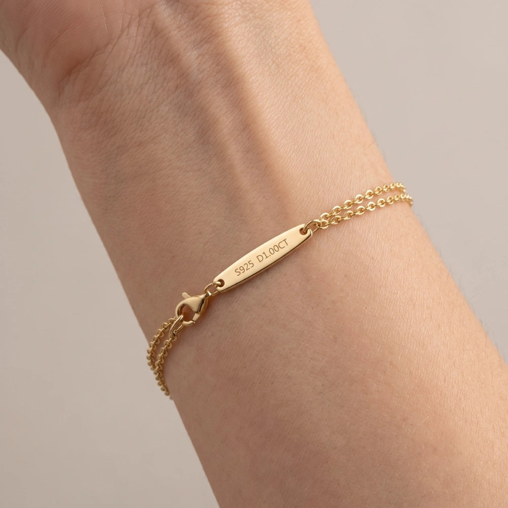 A yellow gold moissanite solitaire double chain bracelet on the wrist, showing the lobster clasp and S925 engraved bar - Sensitive Stones