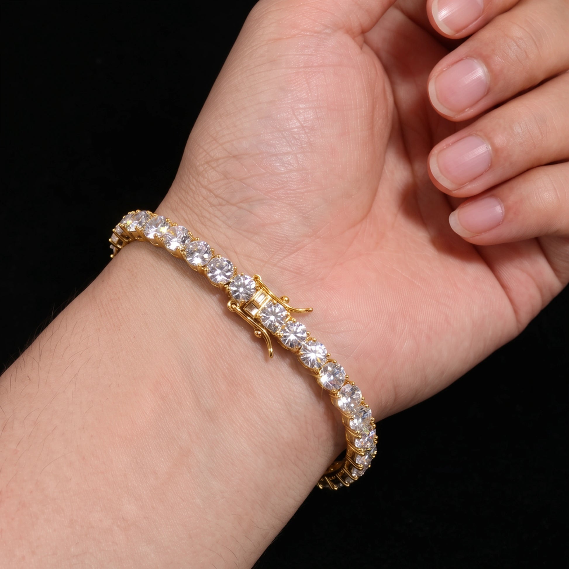 5mm statement moissanite tennis bracelet in 18K yellow gold worn on the wrist, showing the box clasp with double safety and claw set round D Color VVS1 stones - Sensitive Stones
