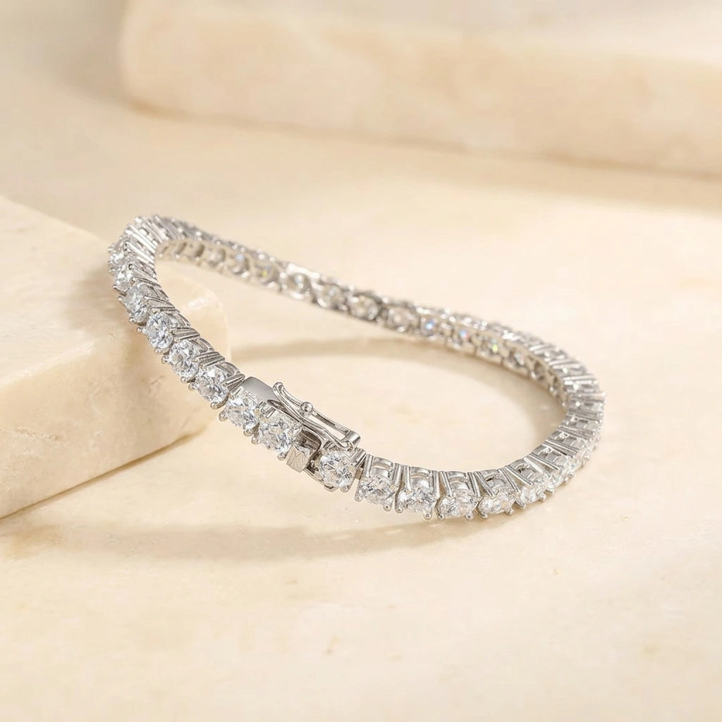 5mm statement moissanite tennis bracelet in 18K white gold draped over a cream marble surface, claw set round D Color VVS1 stones - Sensitive Stones