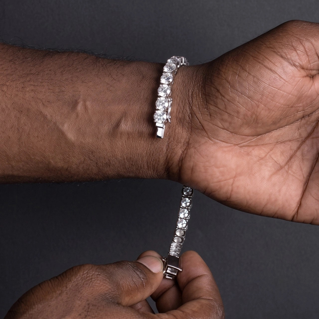 Man wearing the statement moissanite tennis bracelet in 18K white gold, adjusting the box clasp - Sensitive Stones