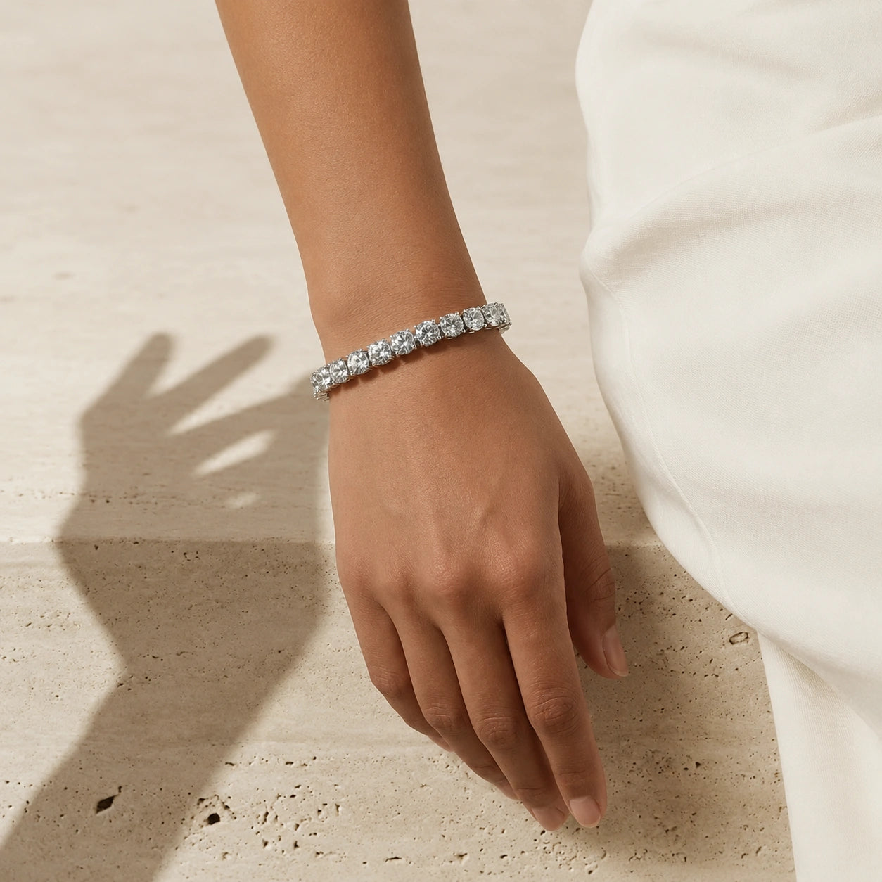 Woman wearing the statement moissanite tennis bracelet in white gold with 6.5mm round D Color VVS1 stones on her wrist - Sensitive Stones