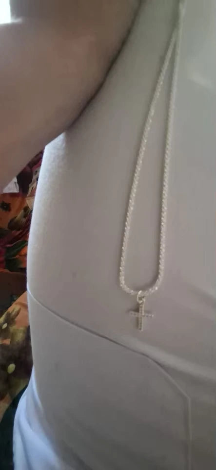 Sterling silver cross pendant chain showcased against a white outfit