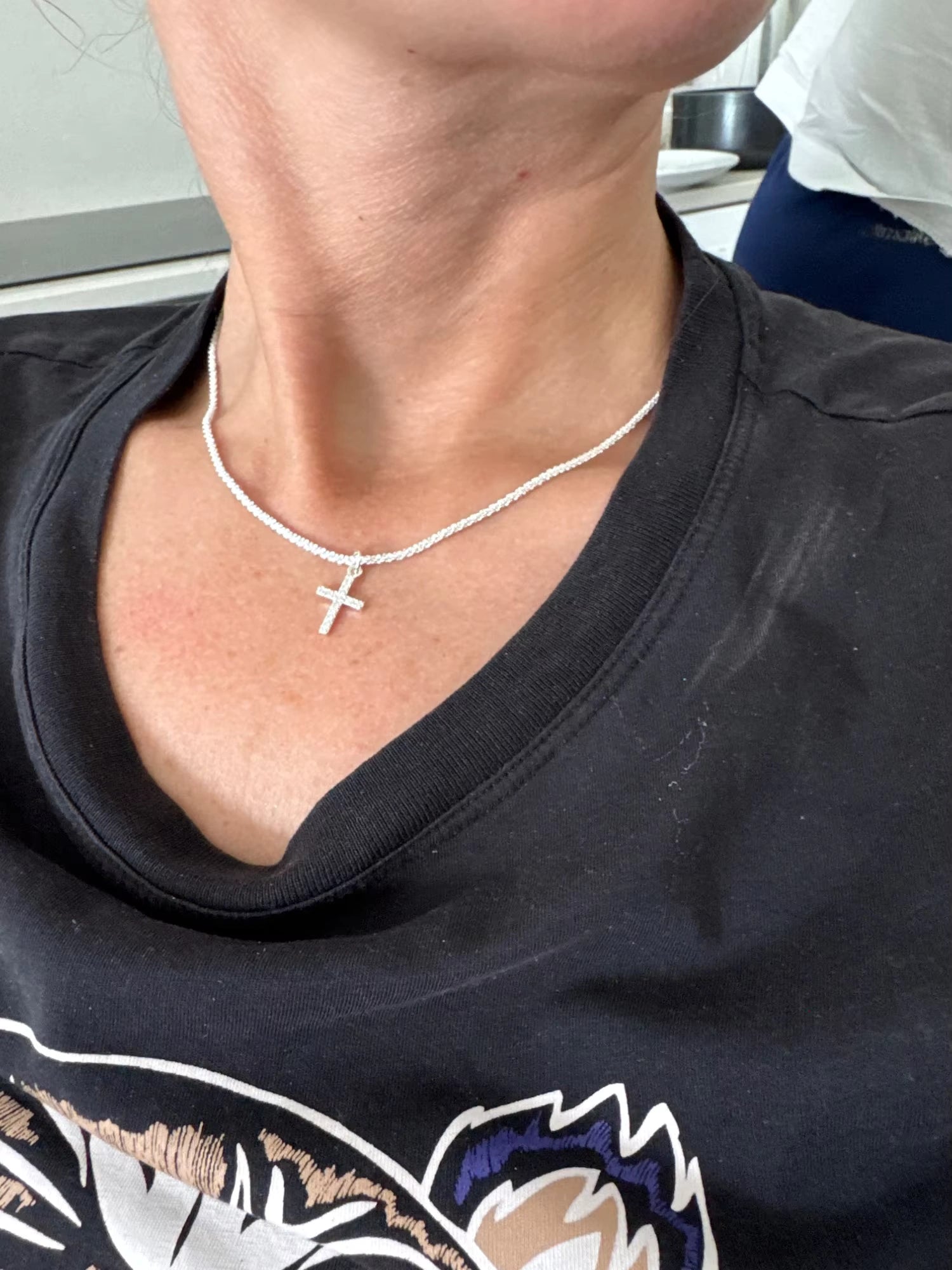 Woman wearing sterling silver cross necklace with a casual black t-shirt