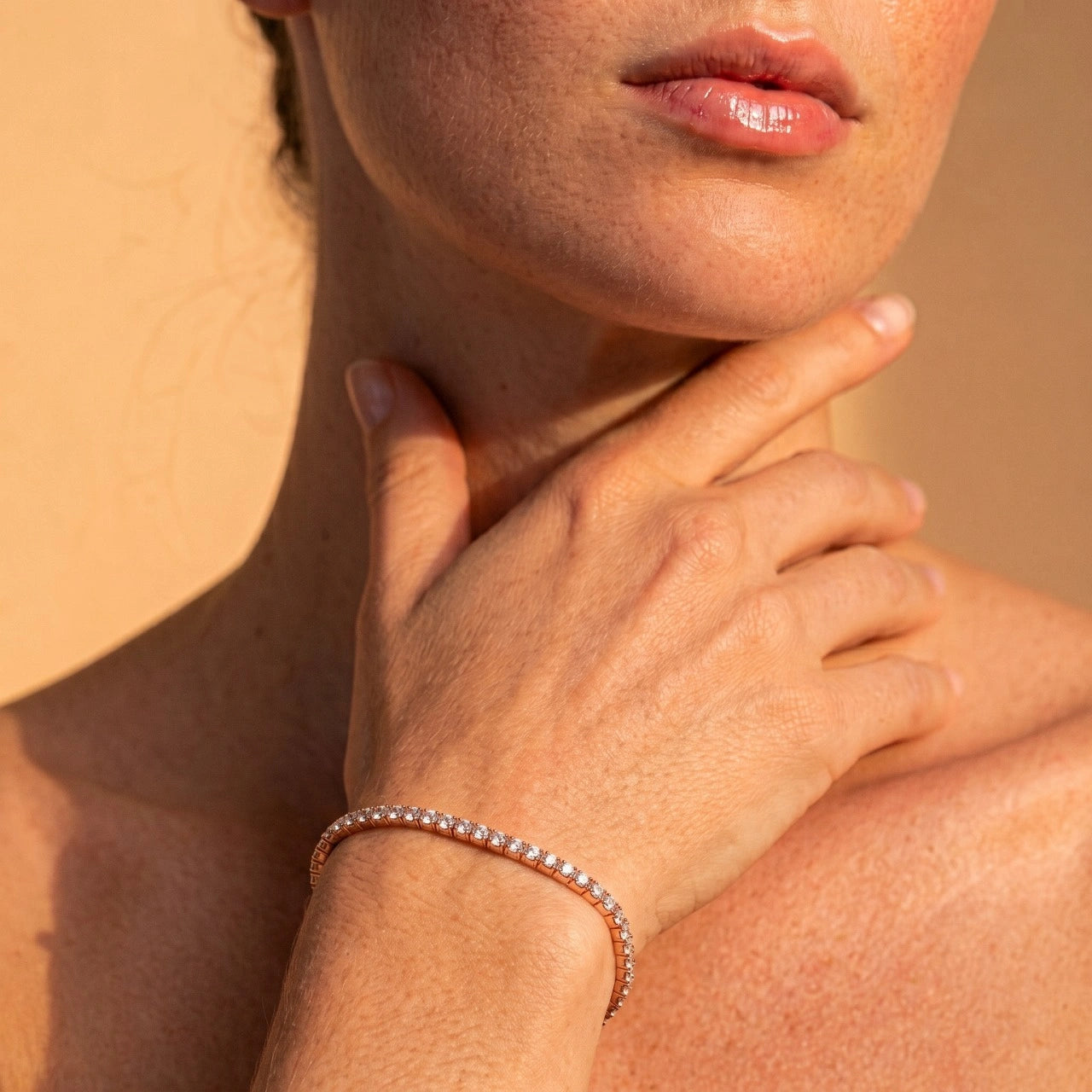 A woman wearing a rose gold stretch moissanite tennis bracelet in warm sunlight - Sensitive Stones