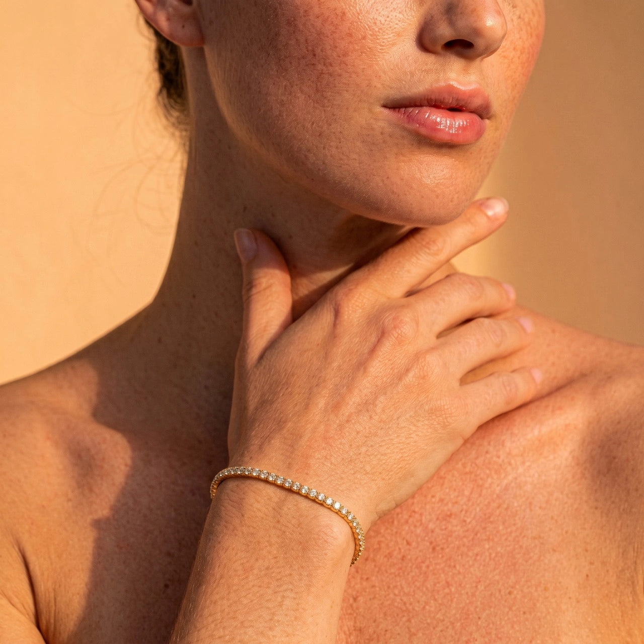 A woman wearing a yellow gold stretch moissanite tennis bracelet in warm sunlight - Sensitive Stones