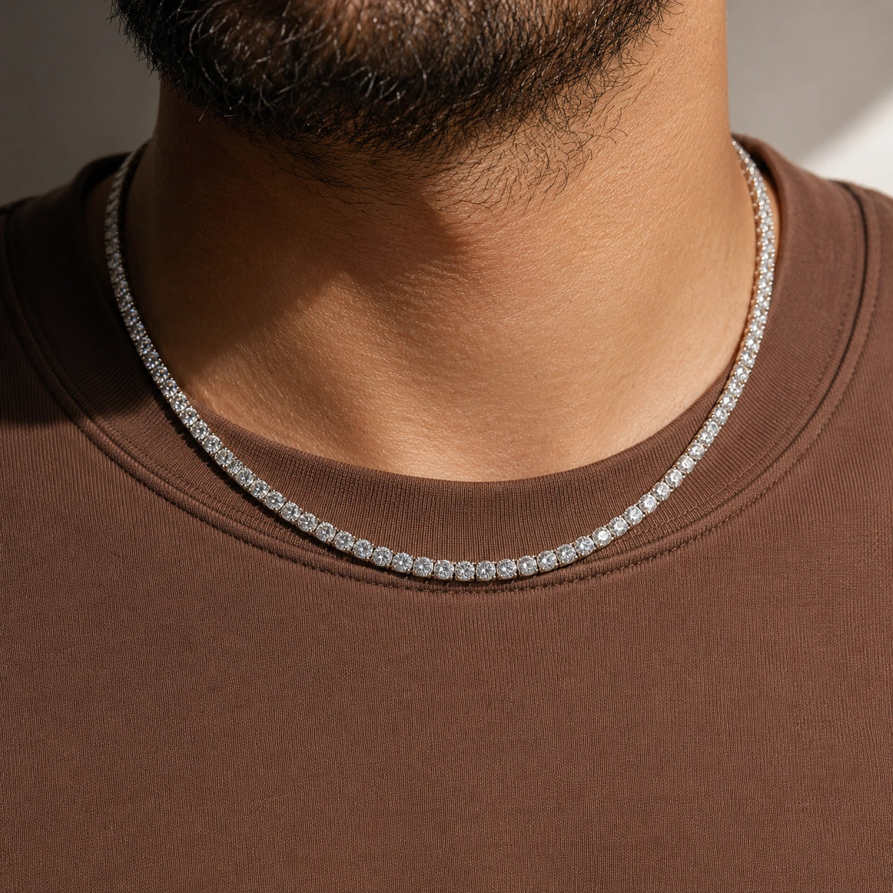 White moissanite tennis necklace worn on male model in brown crew neck, white gold plated 925 sterling silver, 4-prong round stones - Sensitive Stones