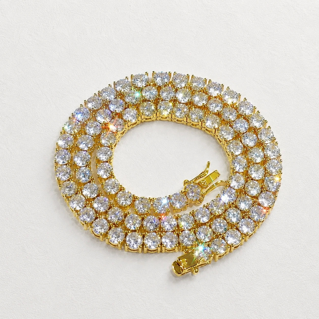 White moissanite tennis necklace in yellow gold plated 925 sterling silver, coiled flat lay showing rainbow fire, 4-prong round stones - Sensitive Stones